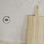 Wooden cutting board against a light, veined Caesarstone surface background with the text ‘Pick a demo space’